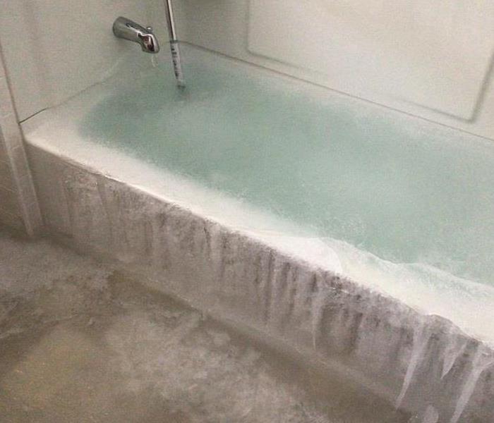 Picture of a bathtub filled with ice from a burst hydronic heat pipe
